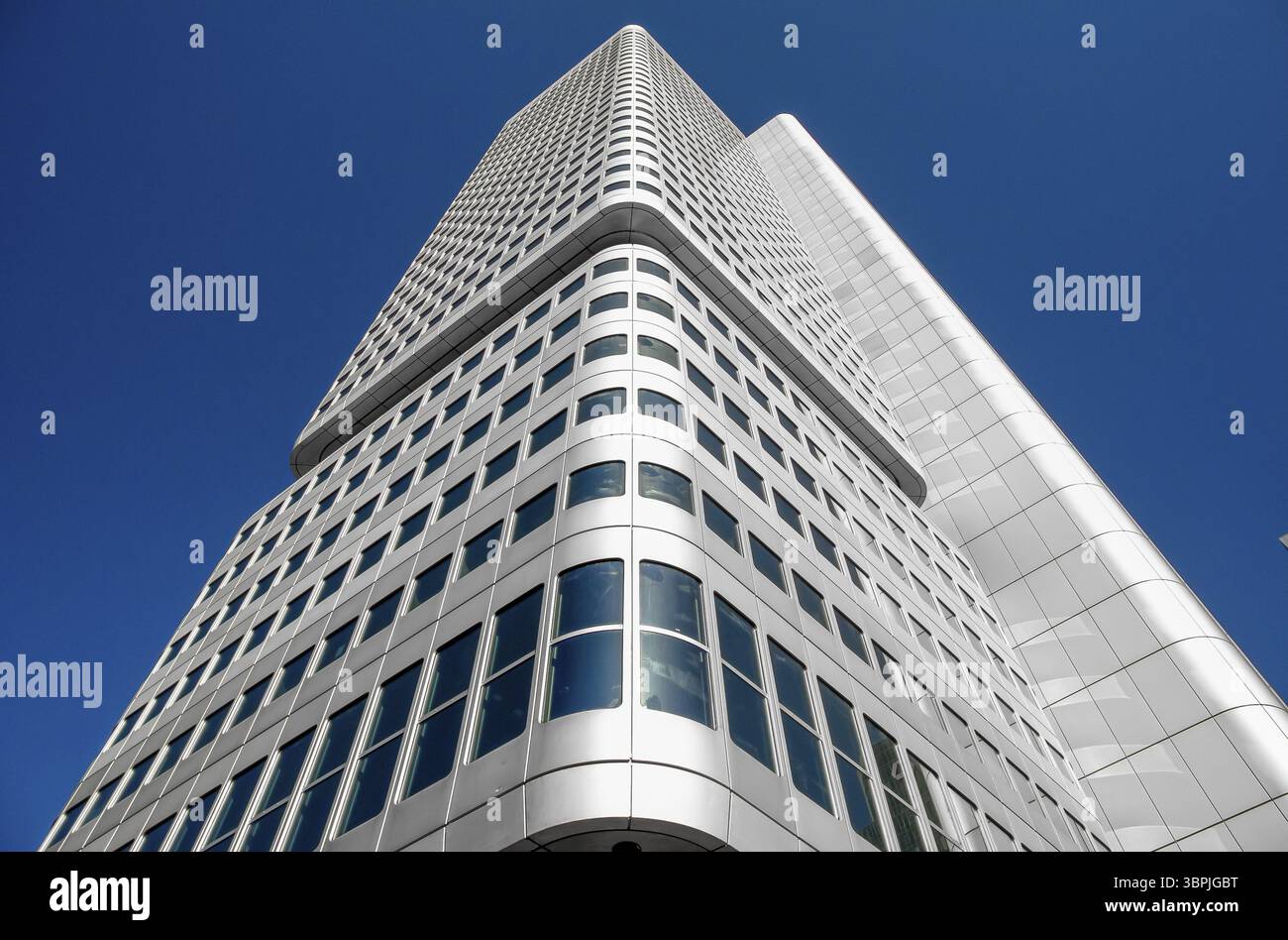 Alta facciata bianca-argentata di una moderna torre di uffici alla luce del sole con cielo blu senza nuvole in vista obliqua del fondo, Francoforte sul meno, Germania Foto Stock