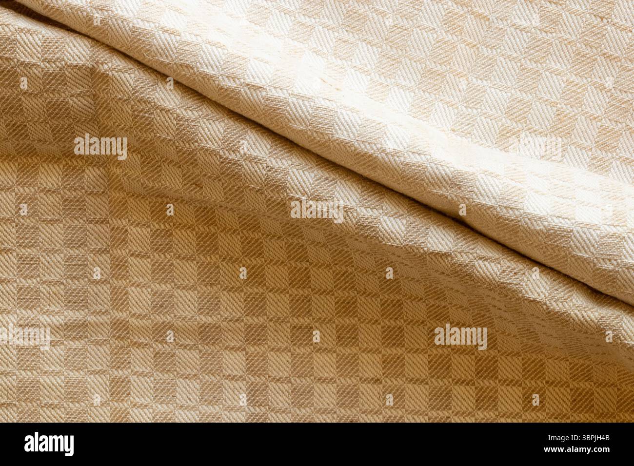 Sfondo in tessuto beige con motivo geometrico a scacchi con due pieghe al centro, texture tessile per interni o design Foto Stock