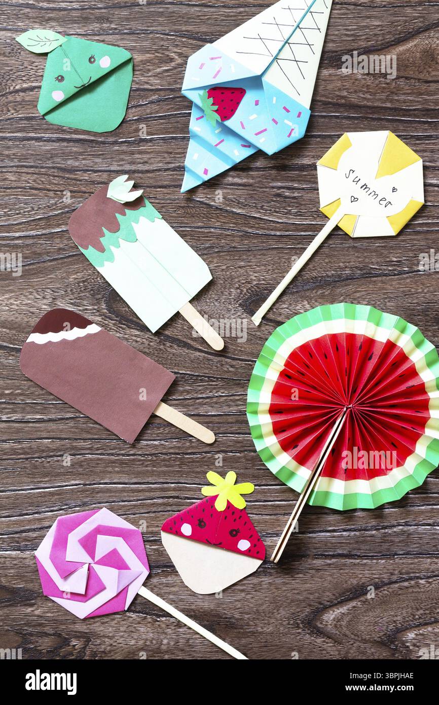 Simpatico giocattolo con lecca lecca, anguria, gelato e segnalibri fragole e mele. Bastoncini di legno per giocattoli di carta estivi su un tavolo di legno. Progetto artistico per bambini Foto Stock Simpatico giocattolo con lecca lecca, anguria, gelato e segnalibri fragole e mele. Bastoncini di legno per giocattoli di carta estivi su un tavolo di legno. Progetto artistico per bambini Foto Stock