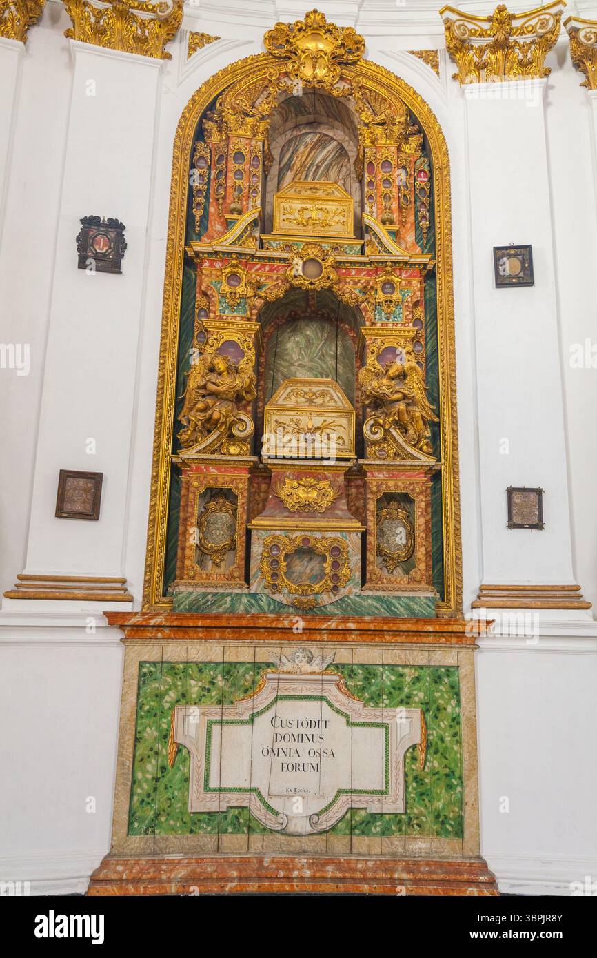 Un altare riccamente decorato con intricate incisioni dorate, iconografia religiosa e un'iscrizione latina, adagiata su un vibrante sfondo piastrellato verde Foto Stock