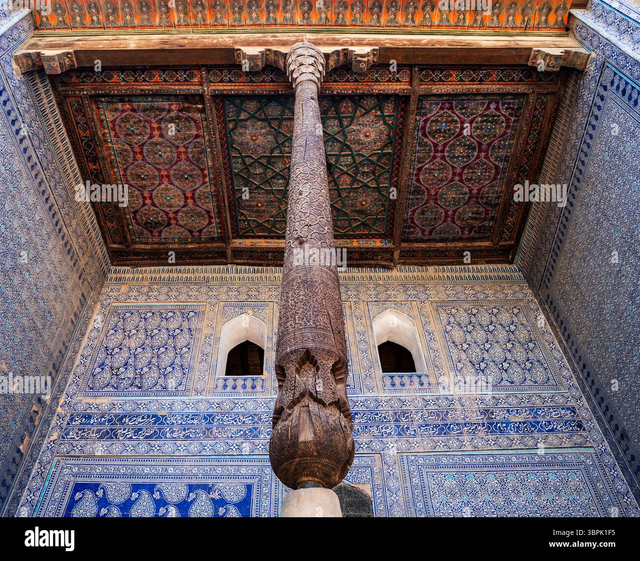 Una splendida vista di un soffitto dal design intricato e di una colonna scolpita in un edificio storico, che mostra motivi ornati e colori vivaci. Foto Stock