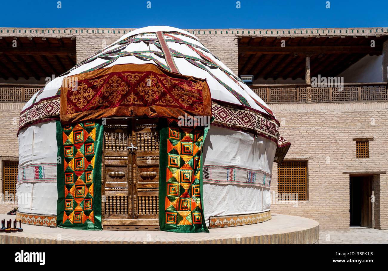 Una yurta tradizionale con un ingresso colorato, adagiata su un cielo azzurro. La struttura presenta motivi intricati e colori vivaci, che mettono in risalto il cu Foto Stock