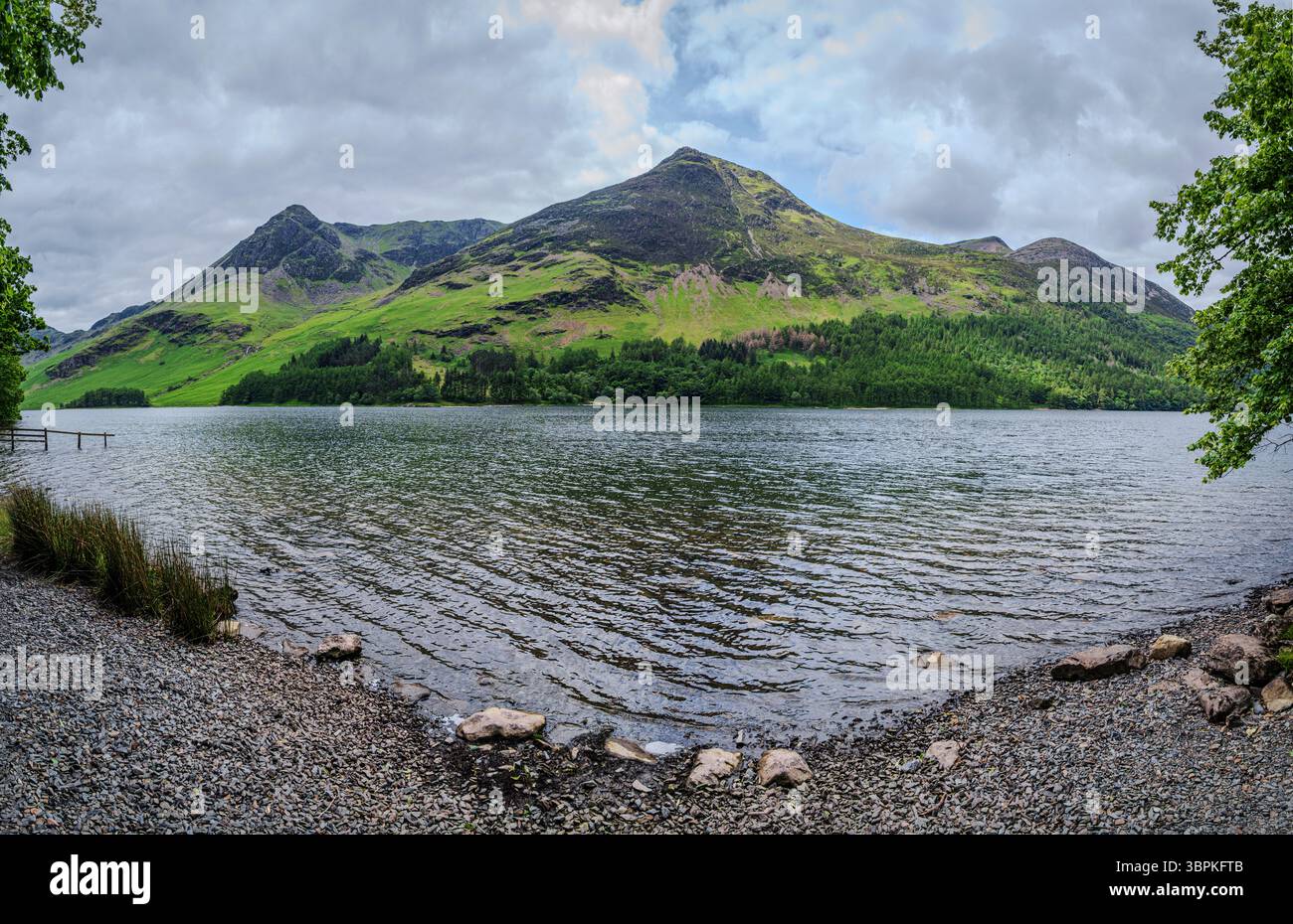 Una giornata nuvolosa al lago Buttermere, con dolci onde che si infrangono sull'acqua soffiata dal vento, adagiato su un paesaggio tranquillo e tranquillo Foto Stock