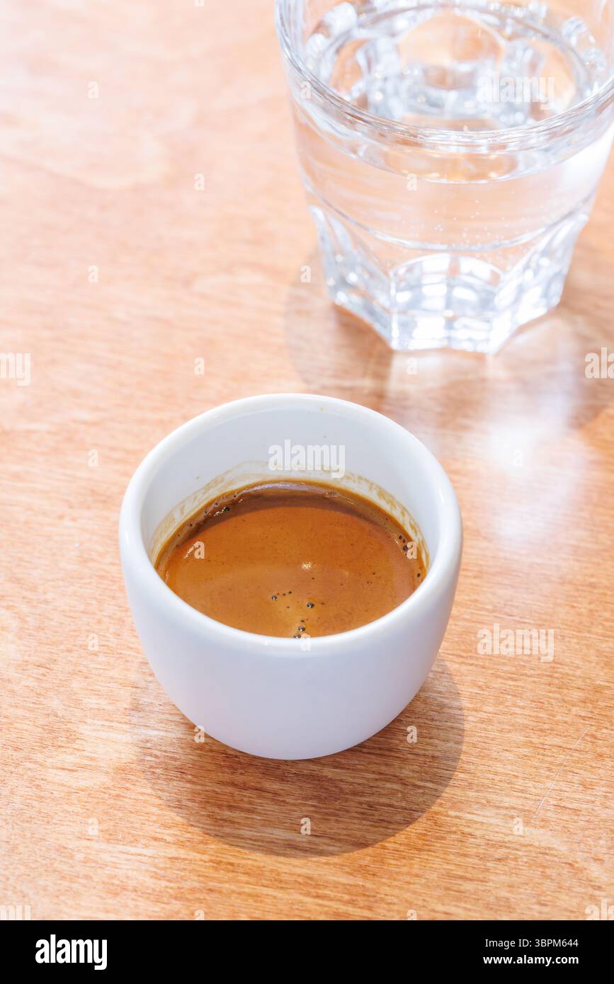 Espresso appena preparato servito in una piccola tazza su un tavolo, catturando l'aroma ricco e il sapore audace di un caffè perfetto Foto Stock