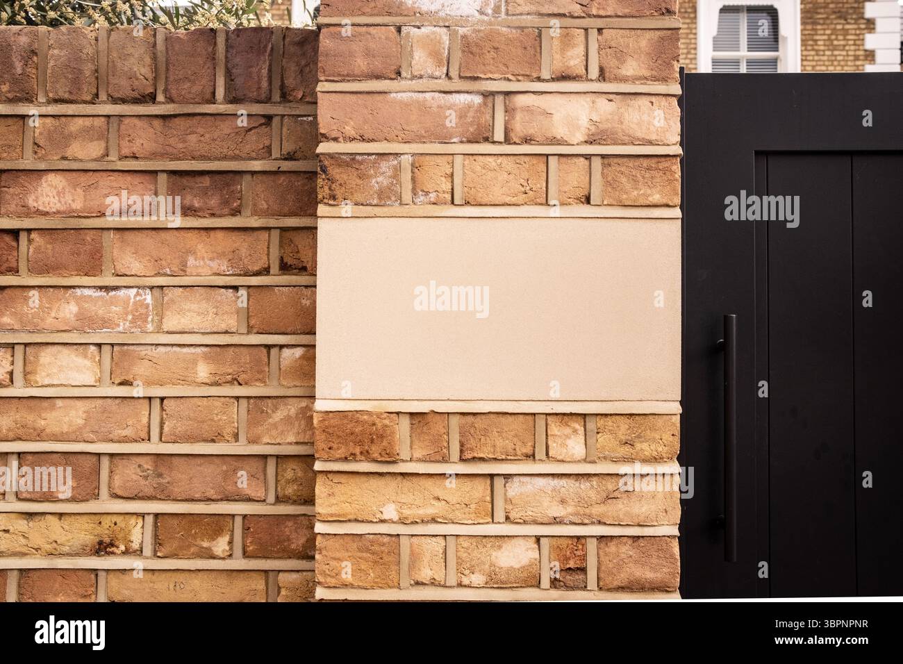 Muro in mattoni con cartello nero con spazio per la copia sulla casa residenziale britannica Foto Stock