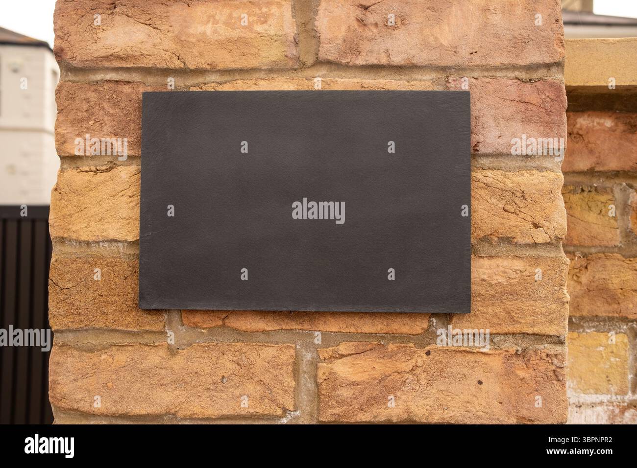 Muro in mattoni con cartello nero con spazio per la copia sulla casa residenziale britannica Foto Stock