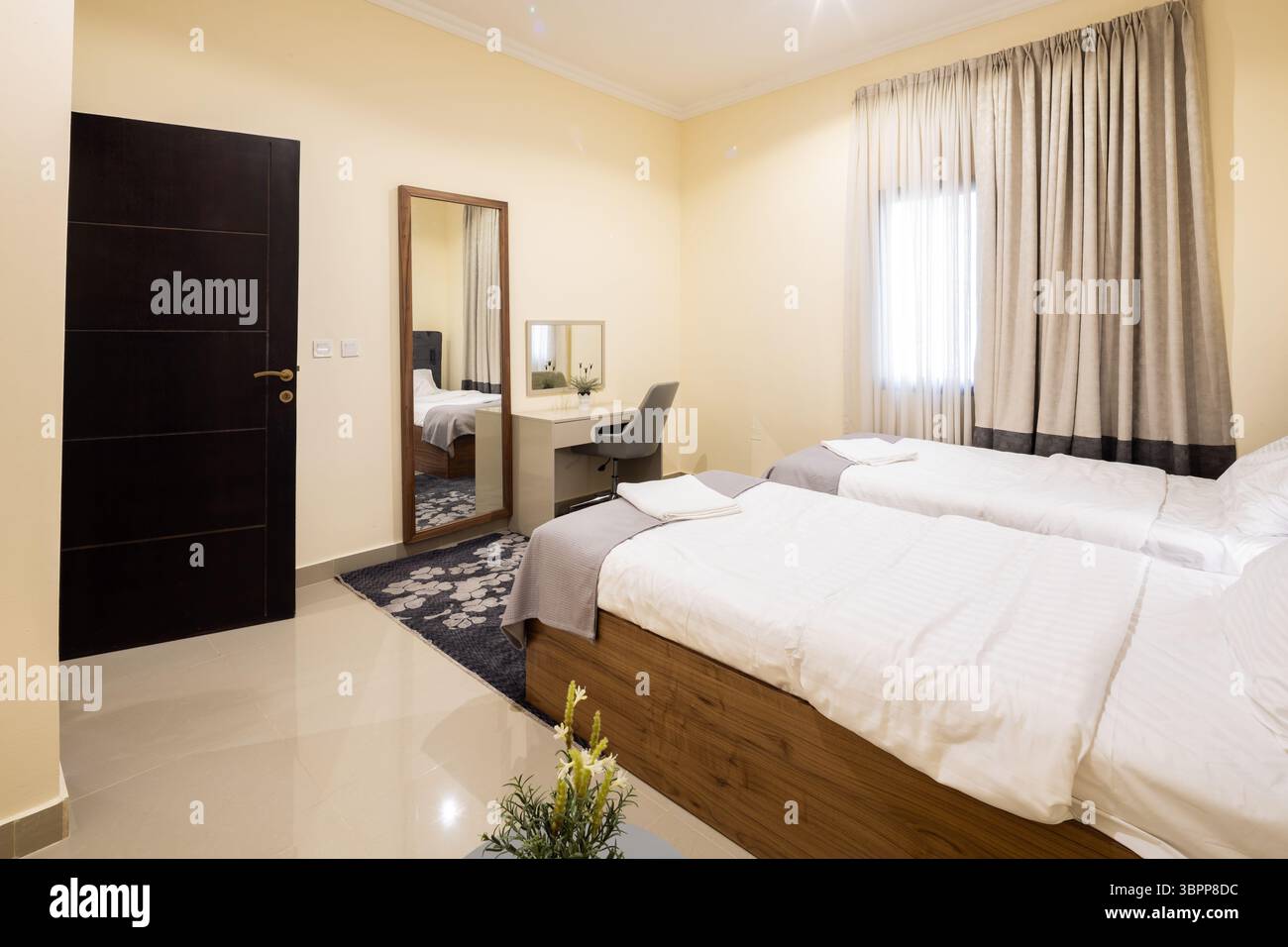 Comoda camera da letto con due letti singoli, interni dal design moderno e illuminazione calda. Foto Stock