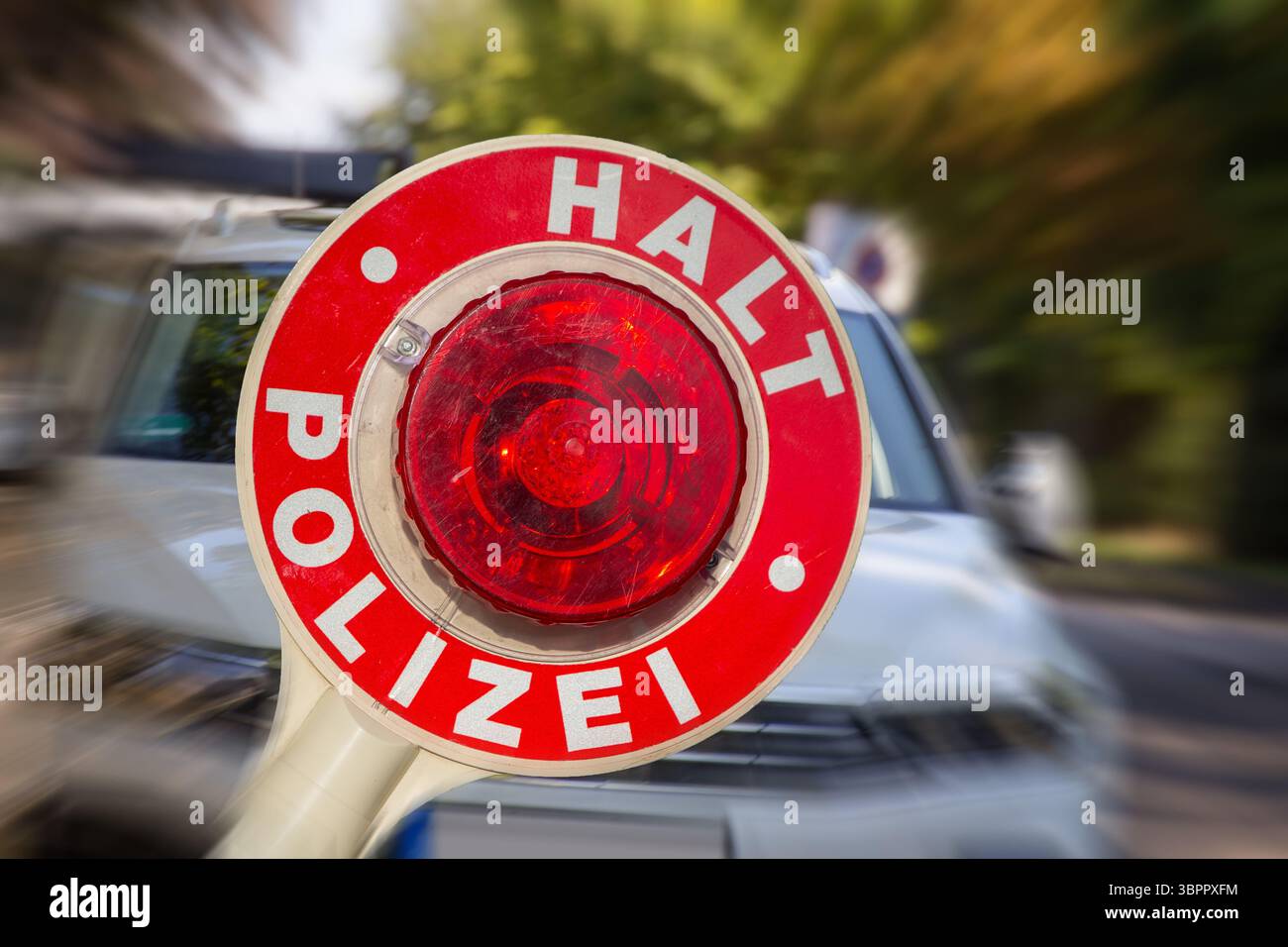 (Fotomontaggio) immagine simbolica di un controllo di polizia: Primo piano di una cazzuola della polizia etichettata HALT POLIZEI davanti a un'auto Foto Stock (Fotomontaggio) immagine simbolica di un controllo di polizia: Primo piano di una cazzuola della polizia etichettata HALT POLIZEI davanti a un'auto Foto Stock