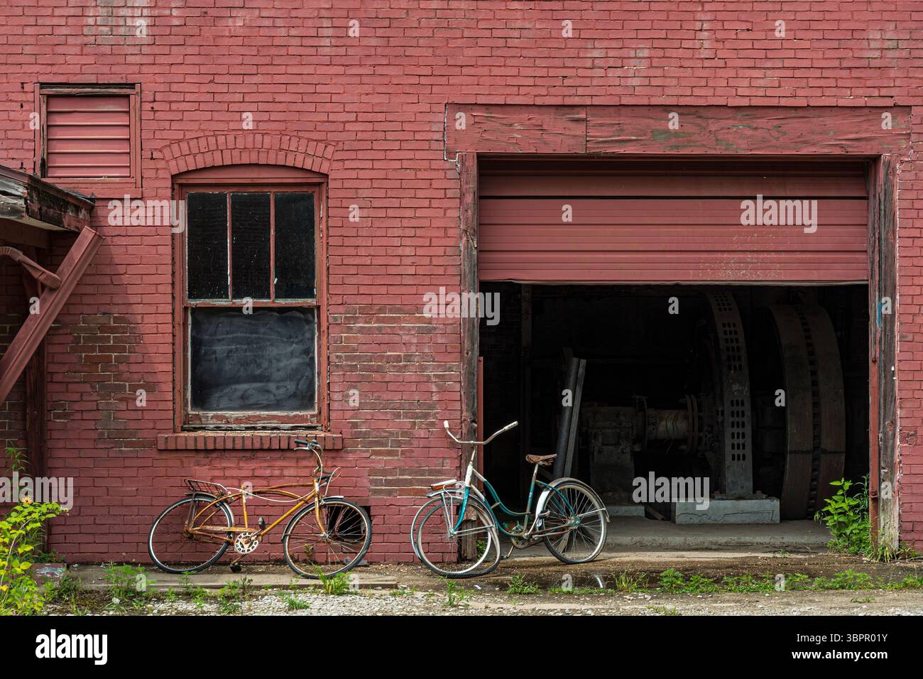 Due biciclette appoggiate su un vecchio edificio in mattoni abbandonato, Indiana USA Foto Stock