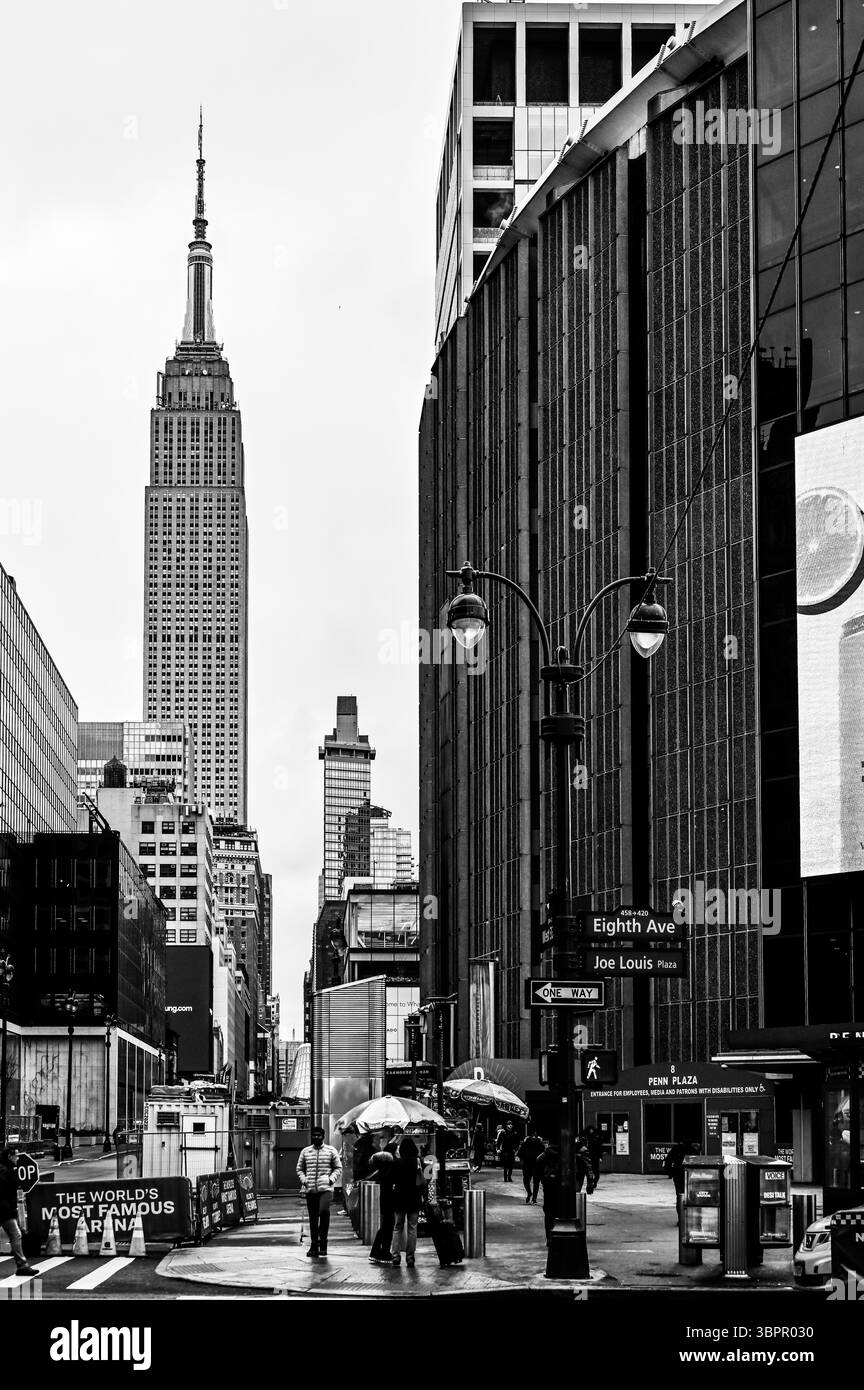 Vista in bianco e nero della Eighth Avenue e dell'Empire State Building con attività di strada a New York City, USA Foto Stock