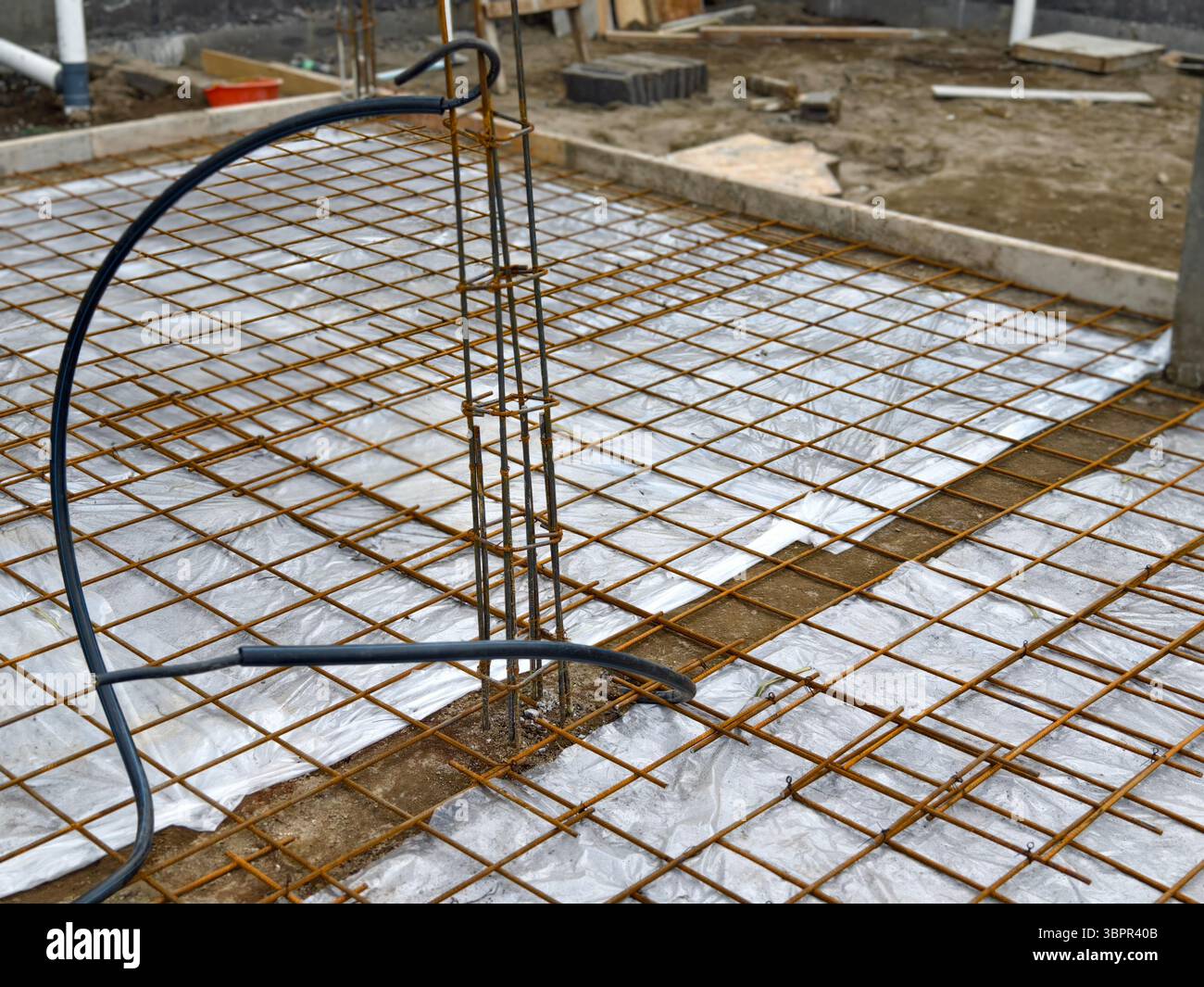 Griglia di rinforzo in acciaio o armatura installata su fogli di plastica prima del versamento del calcestruzzo nel cantiere edile Foto Stock