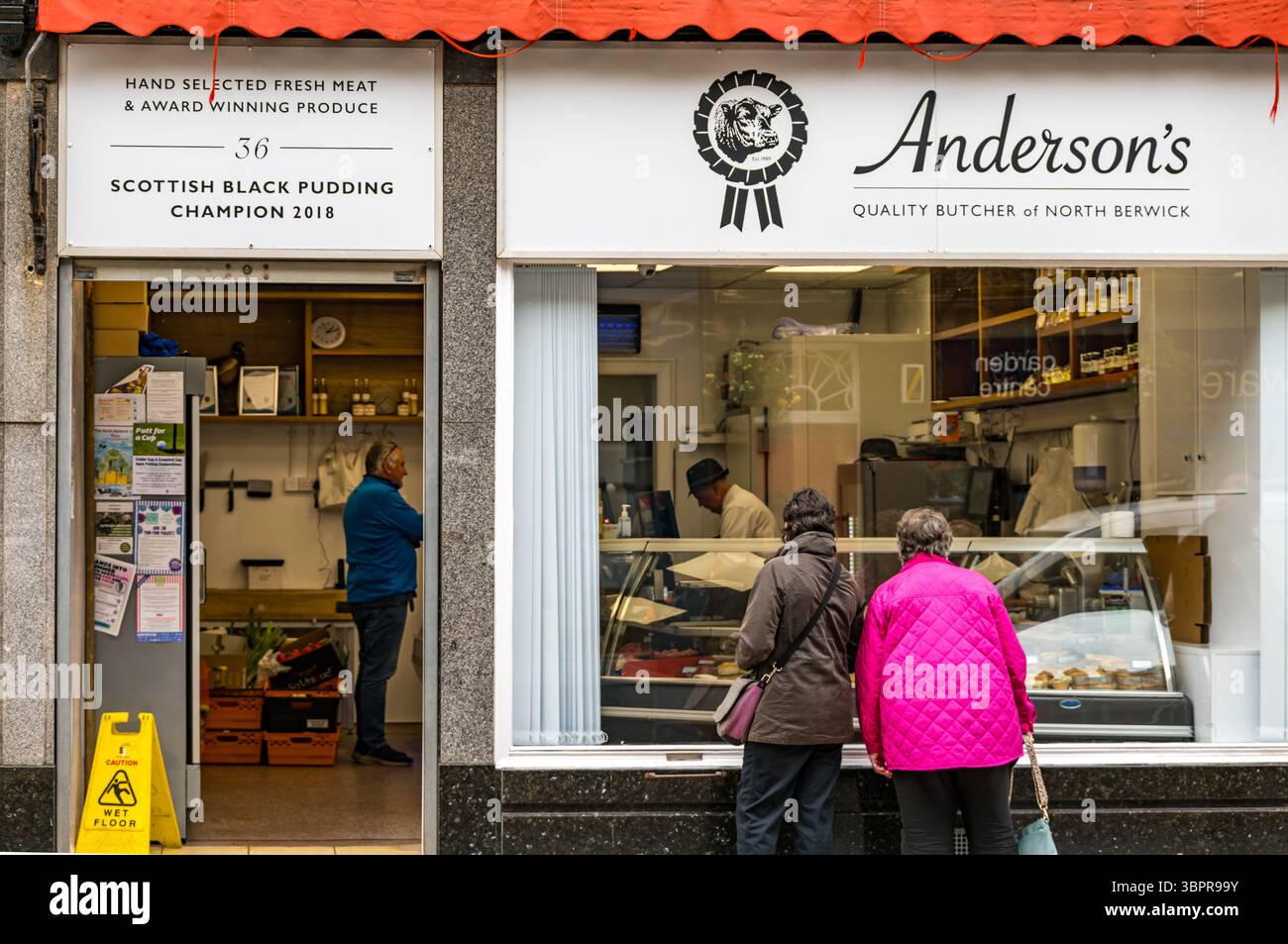Donne che cercano in vetrina, macellerie Anderson's, North Berwick High Street, East Lothian, Scozia, Regno Unito Foto Stock
