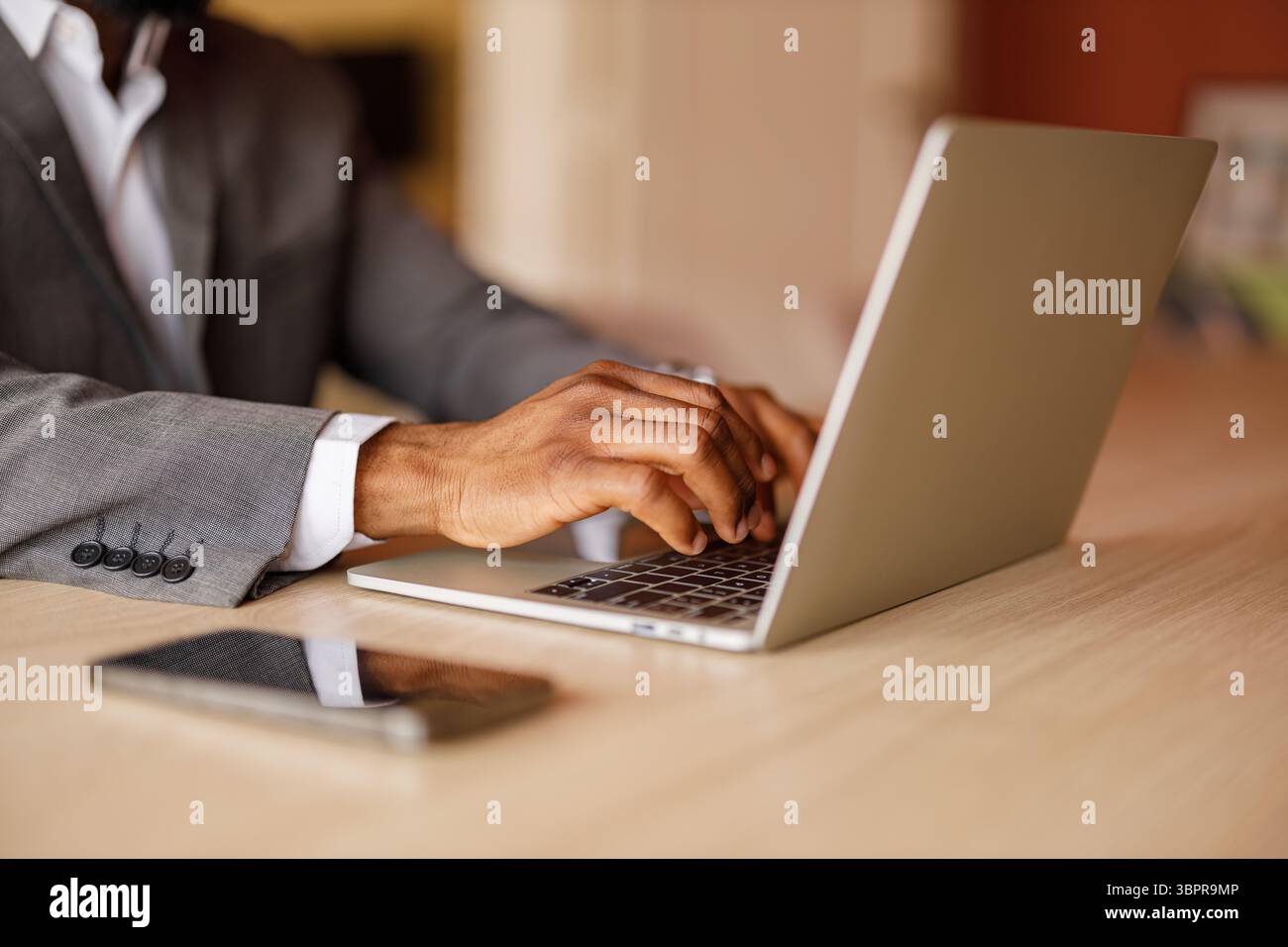 Mani tagliate di un imprenditore maschio che digita e-mail sulla tastiera del laptop alla scrivania dell'ufficio aziendale Foto Stock