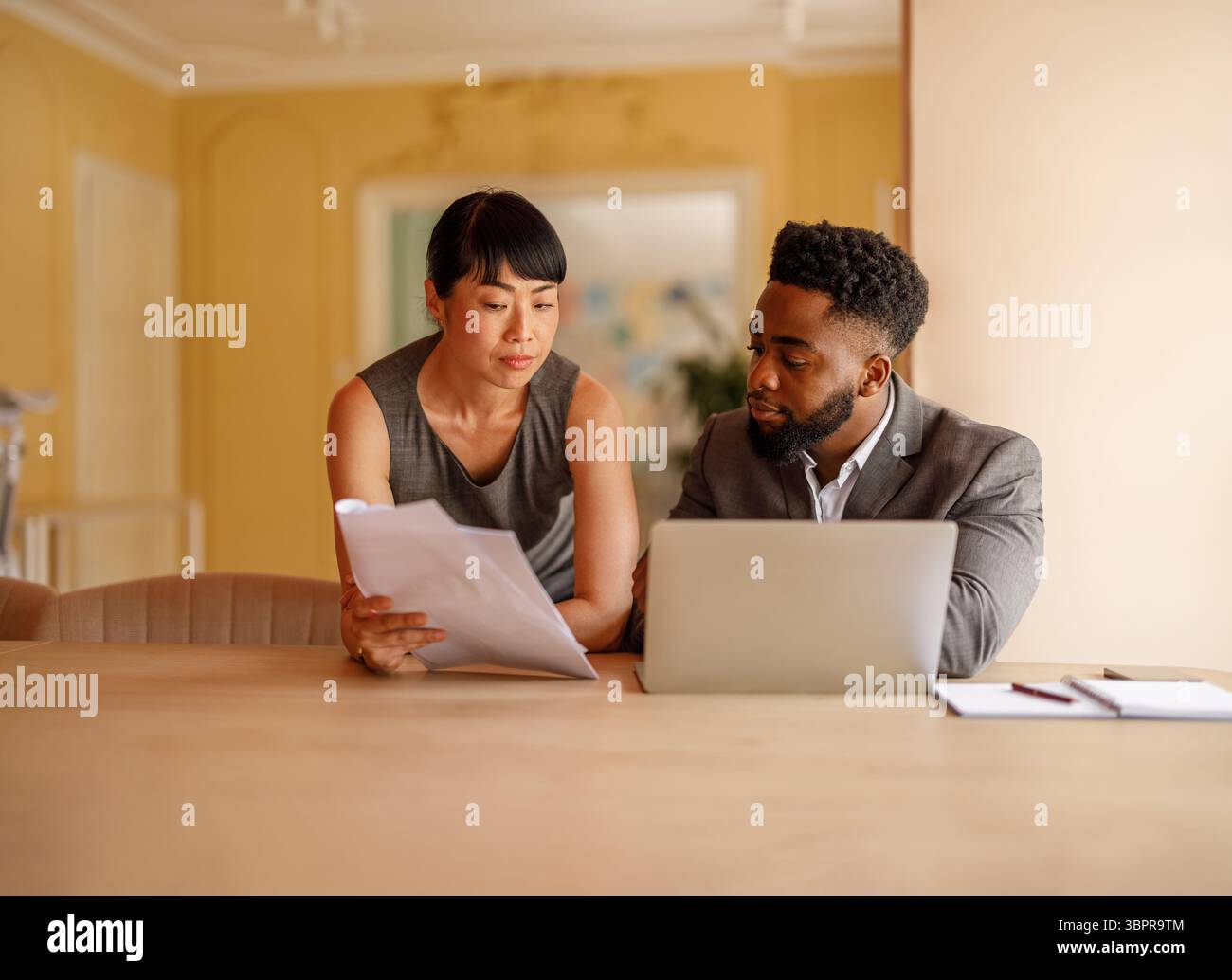 Imprenditori seri che lavorano insieme per esaminare documenti e laptop si concentrano sulla strategia e sull'esecuzione dei progetti in ufficio Foto Stock