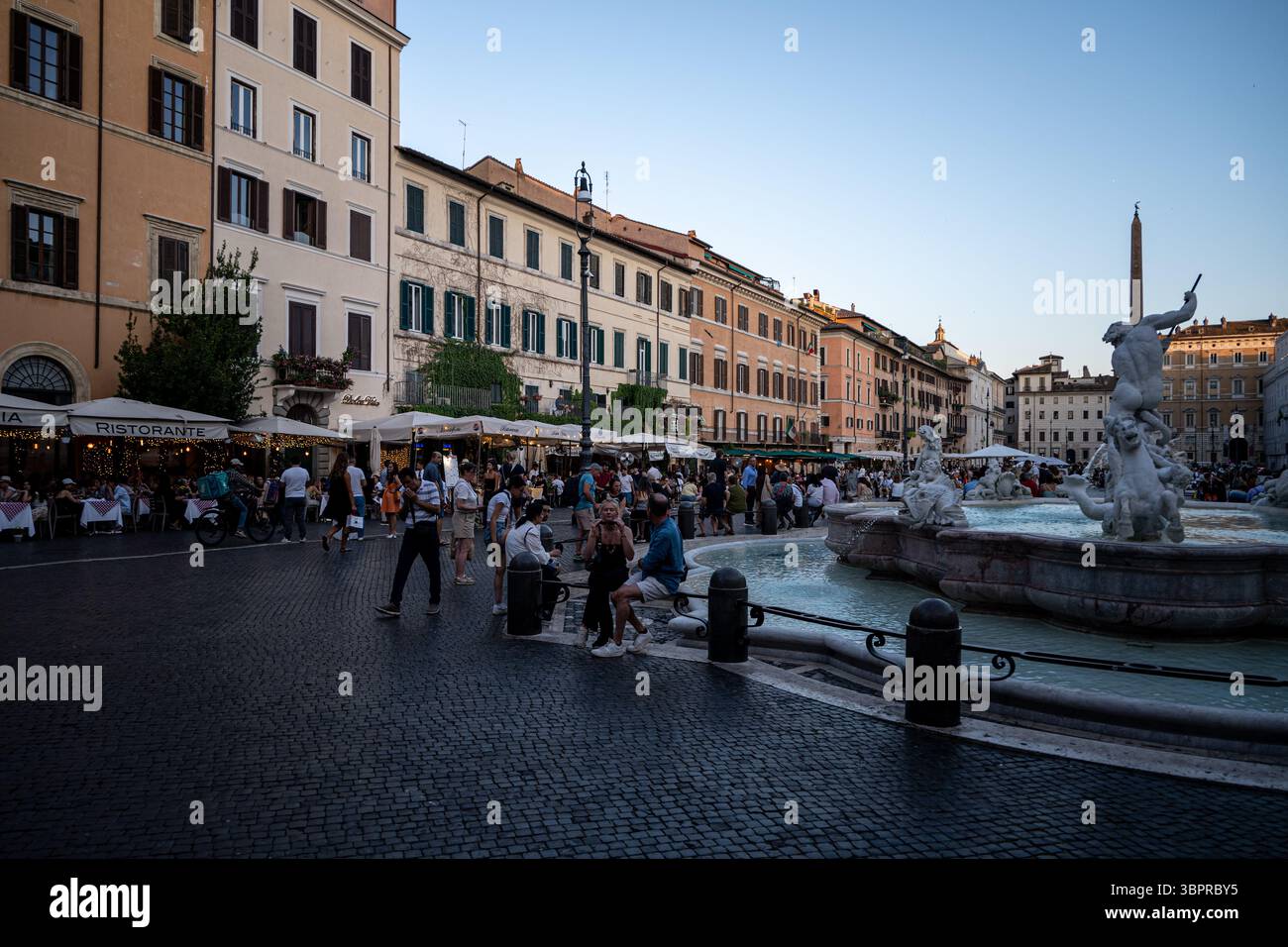 Turisti in un caffè marciapiede in Piazza Navona al crepuscolo, Roma Italia Foto Stock