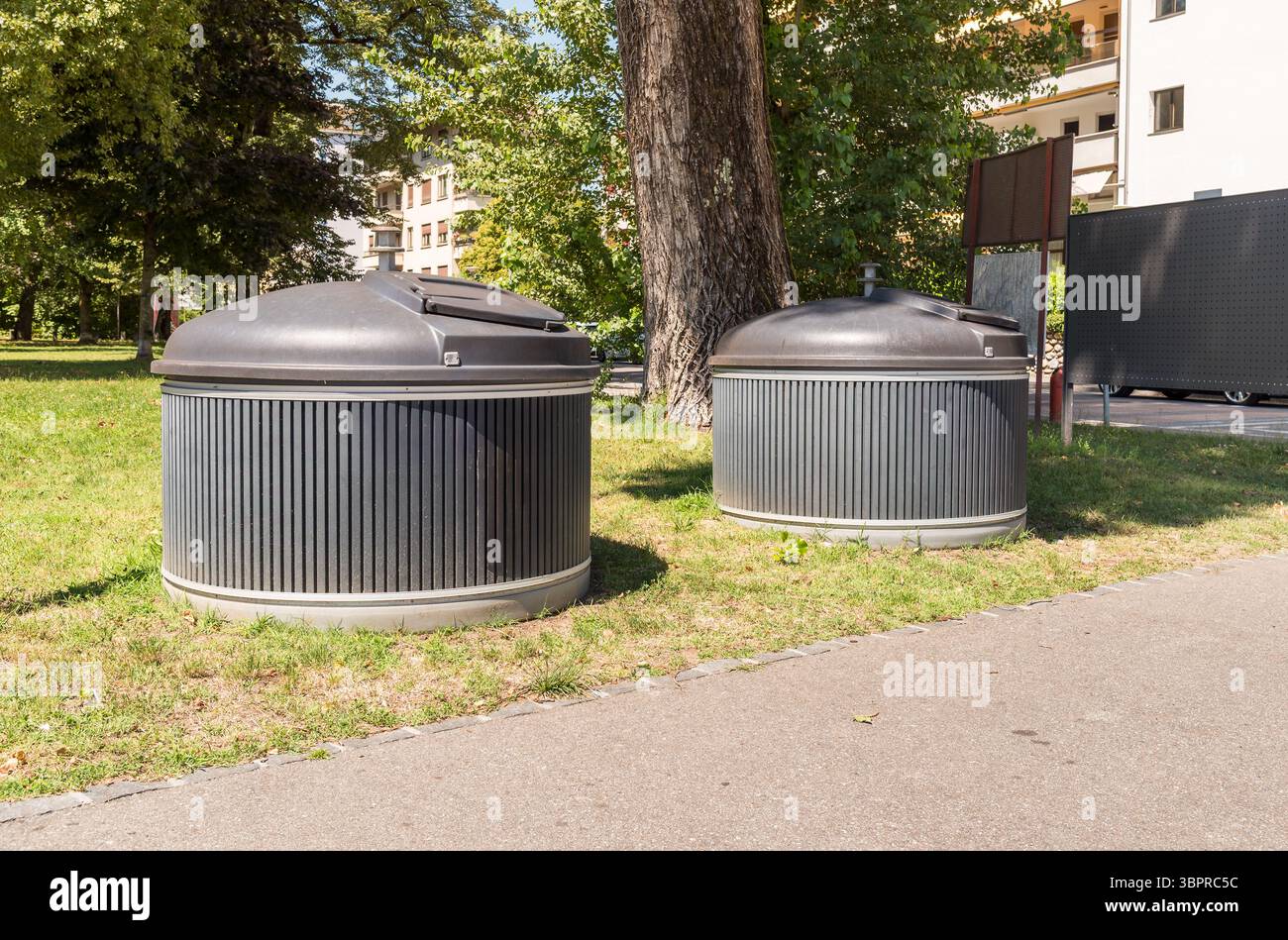 Due grandi bidoni grigi rotondi per lo smistamento dei rifiuti si trovano su una strada della città di Locarno, in Svizzera, nell'ambito di una moderna gestione dei rifiuti urbani Foto Stock