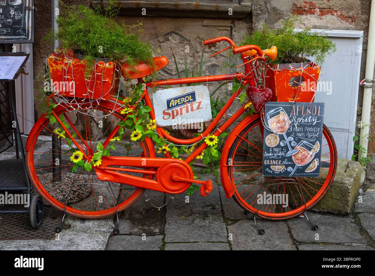 Pisa, Italia - 15 aprile 2025: Un bicyle arancione che promuove Aperol Spritz nella splendida città di Pisa. Foto Stock
