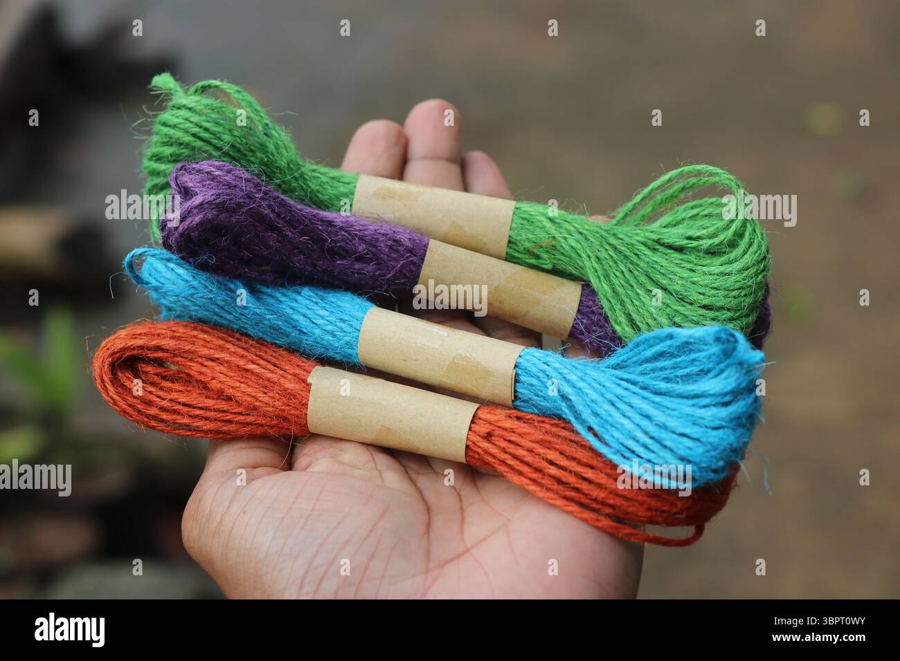 Tenendo un gruppo di spago filettato di iuta multicolore. Corda di iuta colorata per hobby e artigianato Foto Stock