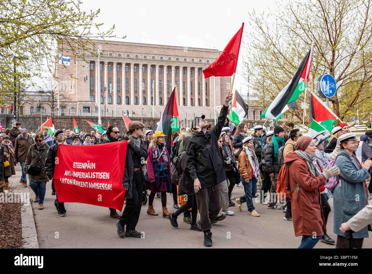 Manifestanti che hanno bandiere palestinesi e bandiere rosse e bandiere rosse al raduno del giorno di maggio a Helsinki, Finlandia Foto Stock