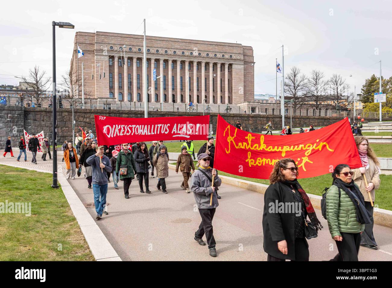 Comunisti che portano striscioni rosse al raduno del giorno di maggio sullo sfondo della camera del Parlamento di Helsinki, Finlandia Foto Stock
