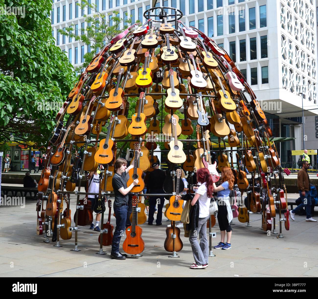 Quest'estate un percorso artistico che celebra la musica conquisterà il centro di Manchester, Regno Unito, con chitarre donate da famosi musicisti, nuove opere d'arte e murales della fermata del tram. Music for the Senses è prodotto dal produttore artistico Wild in Art e presenta più di 80 installazioni e opere d'arte diverse per onorare la fiorente scena musicale di Manchester. Il percorso è attivo dal 7 luglio al 31 agosto. Le installazioni includono questa di Lazerian, costruita con dozzine di chitarre acustiche recuperate in Piazza San Pietro. Foto Stock