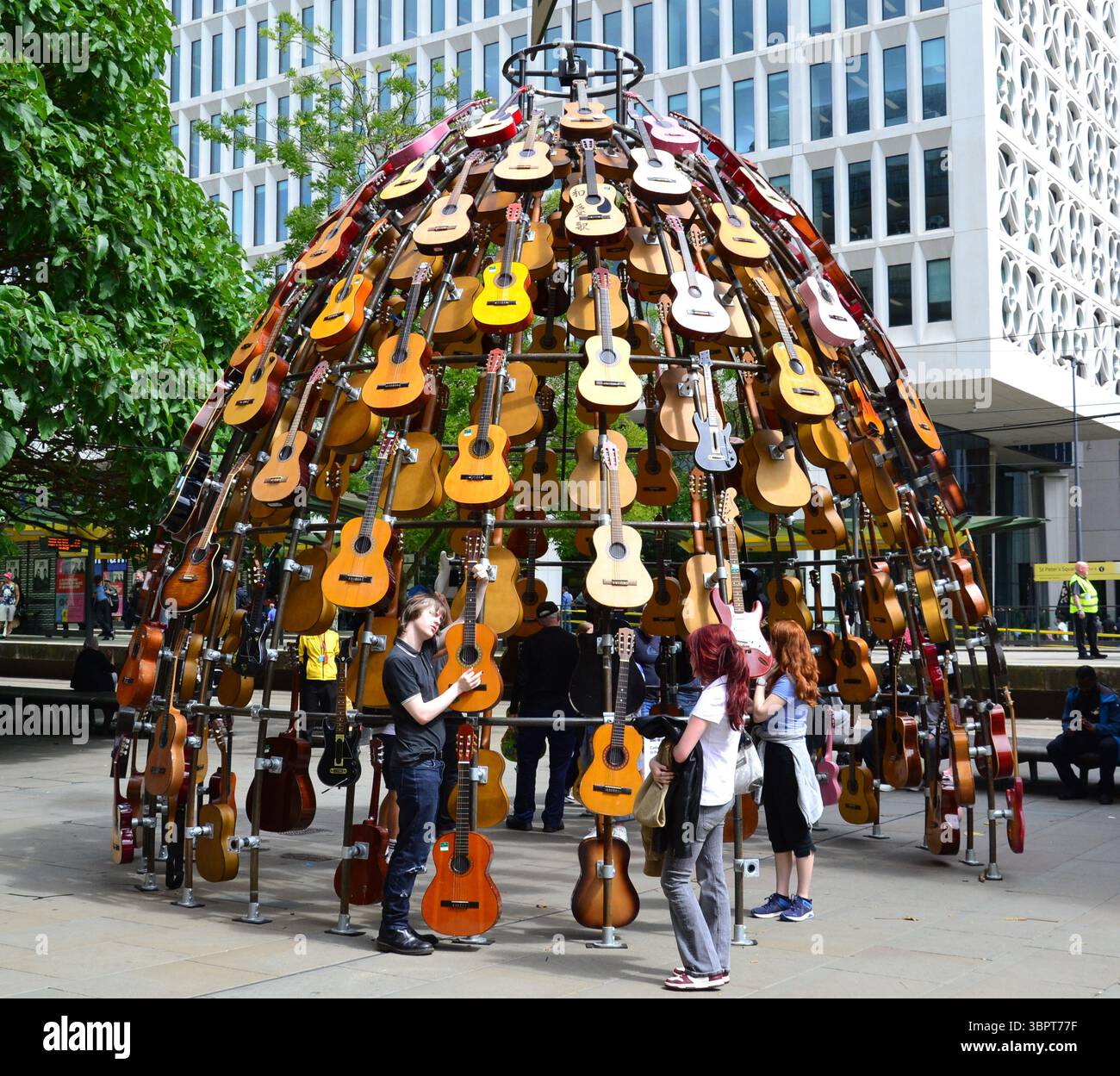 Quest'estate un percorso artistico che celebra la musica conquisterà il centro di Manchester, Regno Unito, con chitarre donate da famosi musicisti, nuove opere d'arte e murales della fermata del tram. Music for the Senses è prodotto dal produttore artistico Wild in Art e presenta più di 80 installazioni e opere d'arte diverse per onorare la fiorente scena musicale di Manchester. Il percorso è attivo dal 7 luglio al 31 agosto. Le installazioni includono questa di Lazerian, costruita con dozzine di chitarre acustiche recuperate in Piazza San Pietro. Foto Stock
