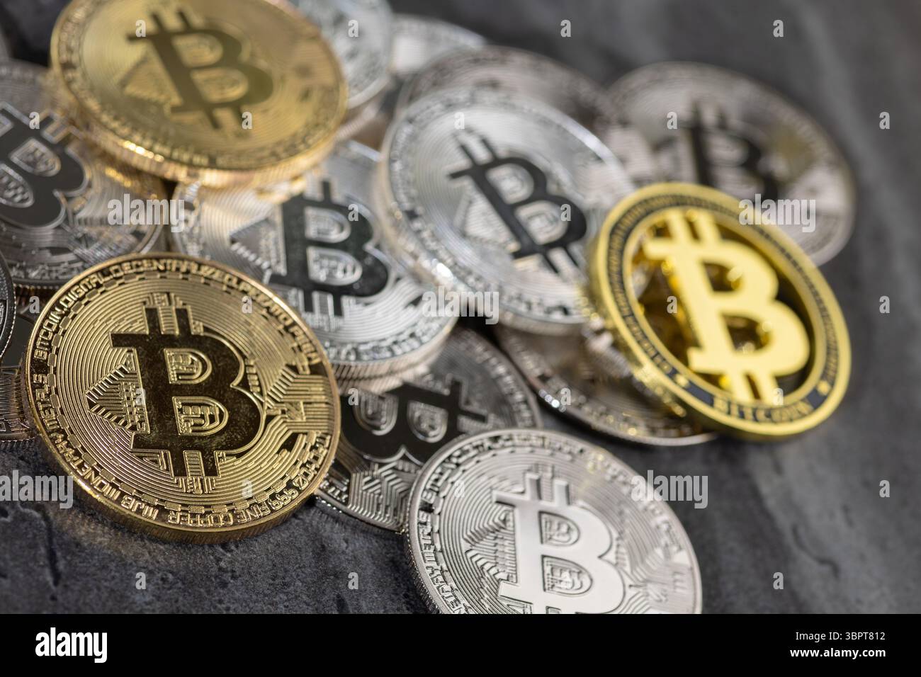 Una disposizione di monete Bitcoin d'oro e d'argento poste su una superficie di pietra testurizzata, simboleggiando concetti di criptovaluta e valuta digitale. Foto Stock