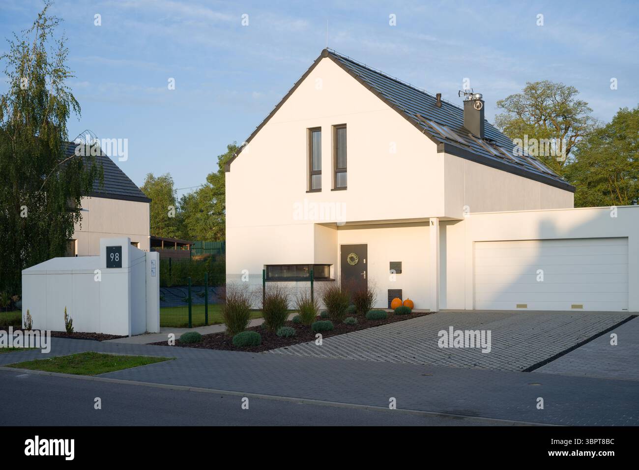 Esterno di una moderna casa unifamiliare con una facciata bianca minimalista e un garage annesso. L'albergo si trova in un tranquillo quartiere periferico Foto Stock