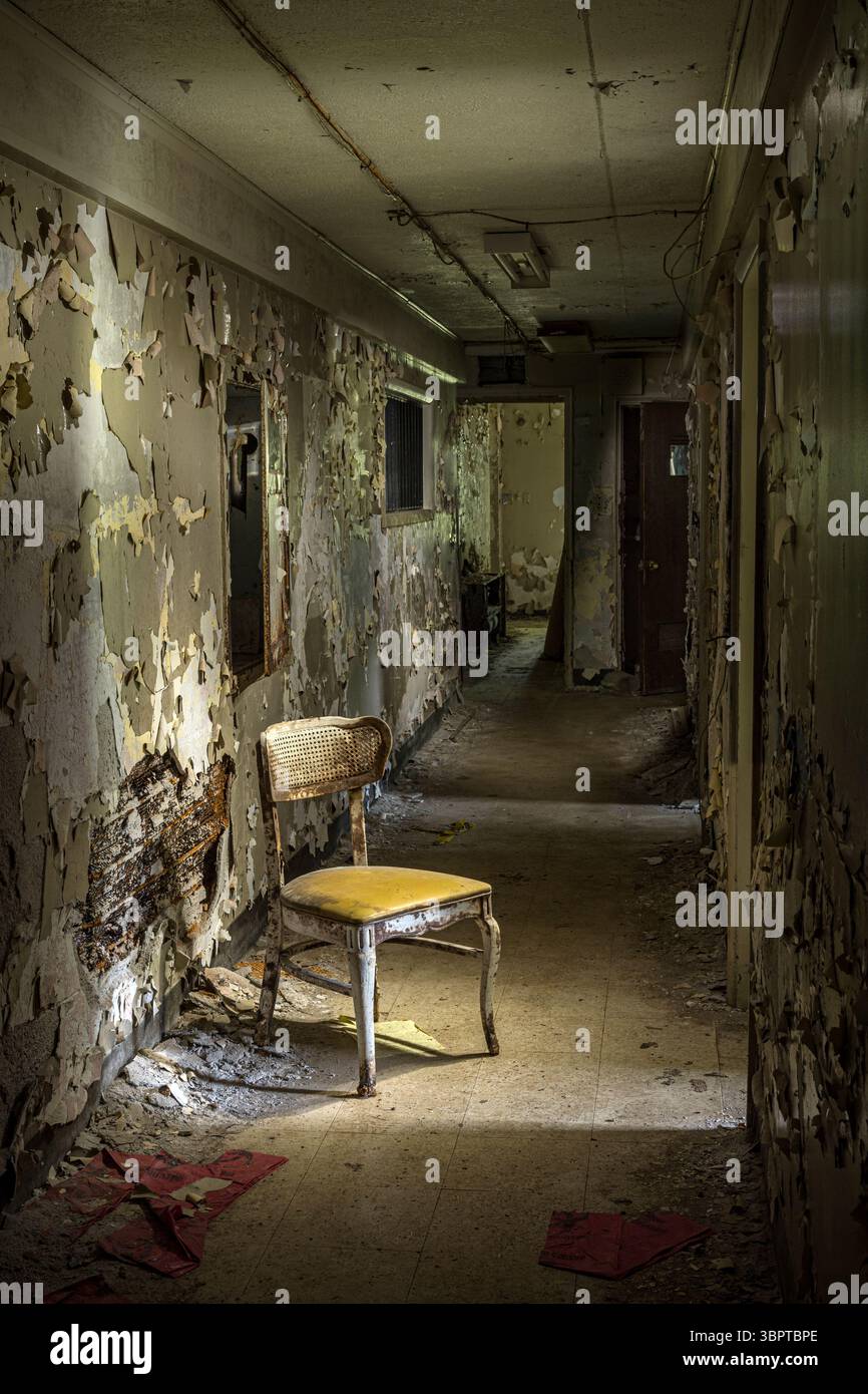 Sedia solitaria in un corridoio buio spaventoso in un edificio abbandonato, Indiana USA Foto Stock