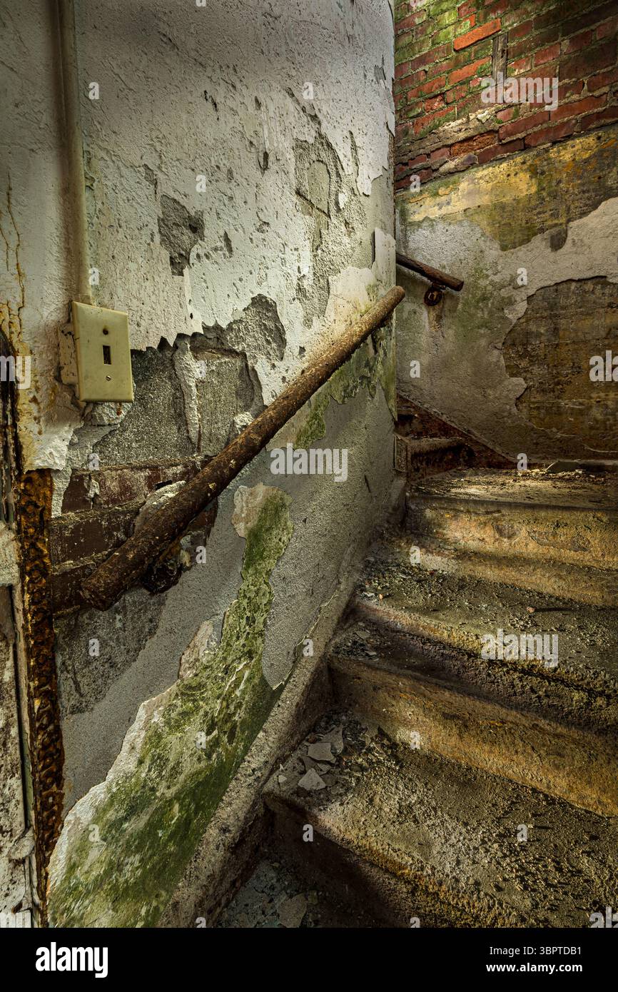 Vernice sbucciata e intonaco scheggiato all'interno delle scale fatiscenti, edificio abbandonato, Rockville Indiana USA Foto Stock