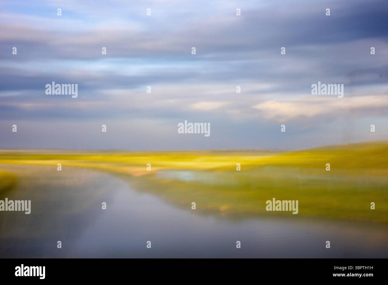Paesaggio astratto della prateria ICM con campi dorati, cieli blu, lago. Foto Stock