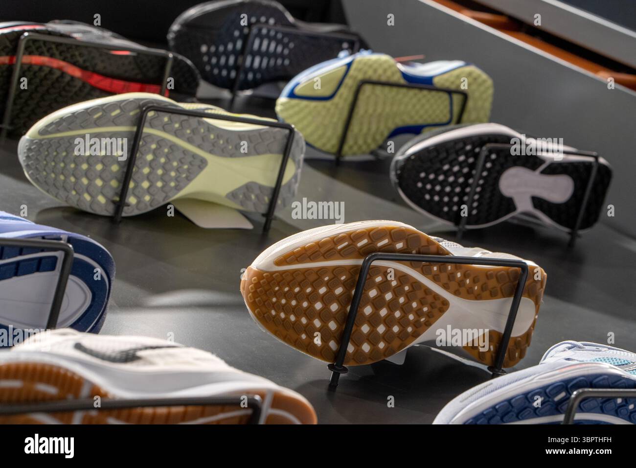 Vista dal basso della vetrina del negozio con una nuova e moderna scarpa da running sulle pareti. Suole di scarpe sportive. Foto Stock