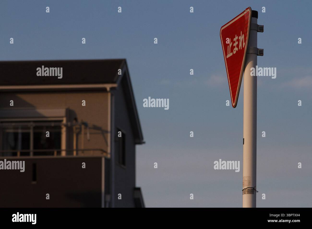 Un segnale di stop in giapponese su una strada con una casa dietro. Kanagawa, Giappone. Foto Stock