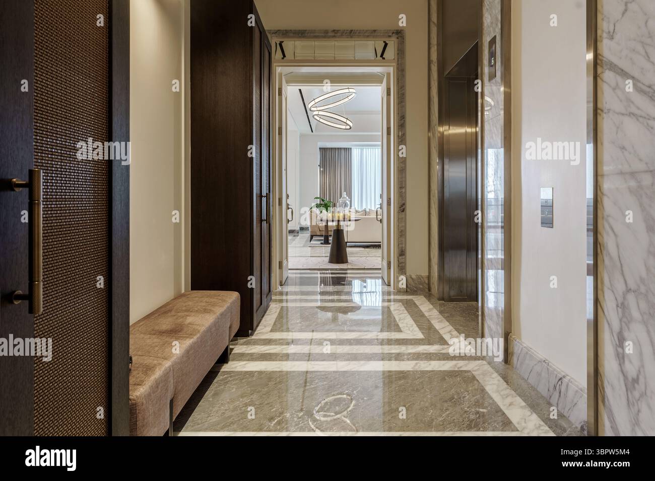 Lussuoso corridoio in un moderno appartamento con pavimenti in marmo, ascensore e vista su un luminoso ed elegante soggiorno. Interni di lusso. Foto Stock