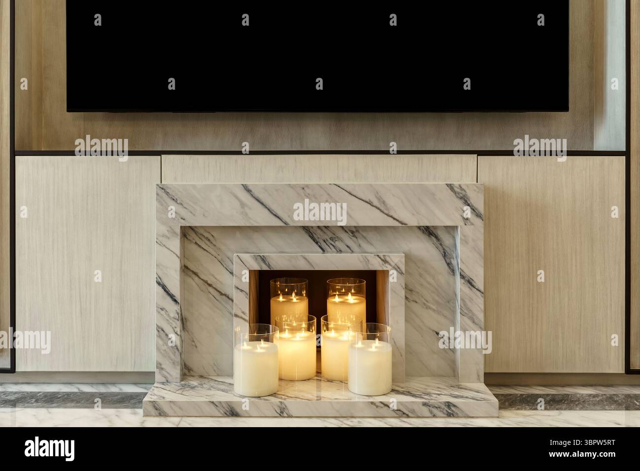 Un moderno camino in marmo pieno di candele luminose in portavetrini in vetro, che creano un ambiente accogliente ed elegante. Un'alternativa elegante a un tradizionale Foto Stock