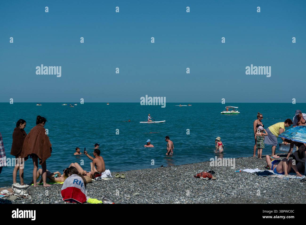 Sochi, Russia - 05 luglio 2022: Turisti che si rilassano sulla spiaggia della città in riva al mare. Attività ricreative turistiche sulla spiaggia di un resort estivo. Foto Stock