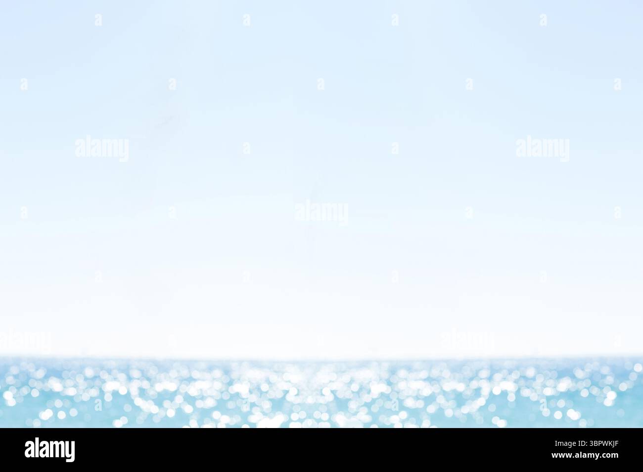 La superficie dell'oceano riflette la luce del sole su onde delicate in un design piatto, cielo azzurro pallido Foto Stock