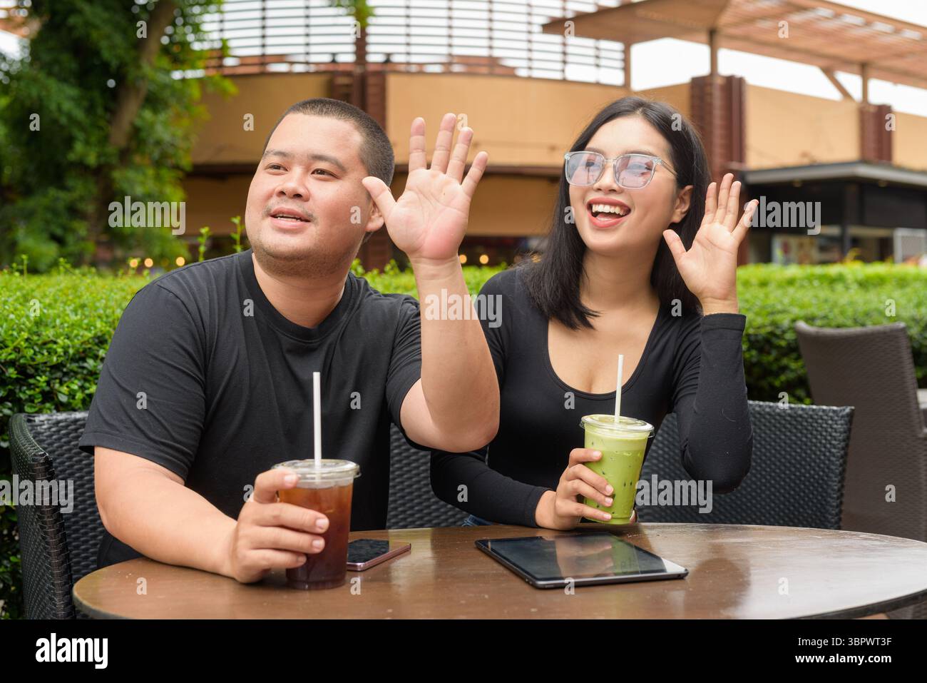 Felice coppia asiatica seduta insieme in un ristorante caffetteria all'aperto durante l'estate Foto Stock
