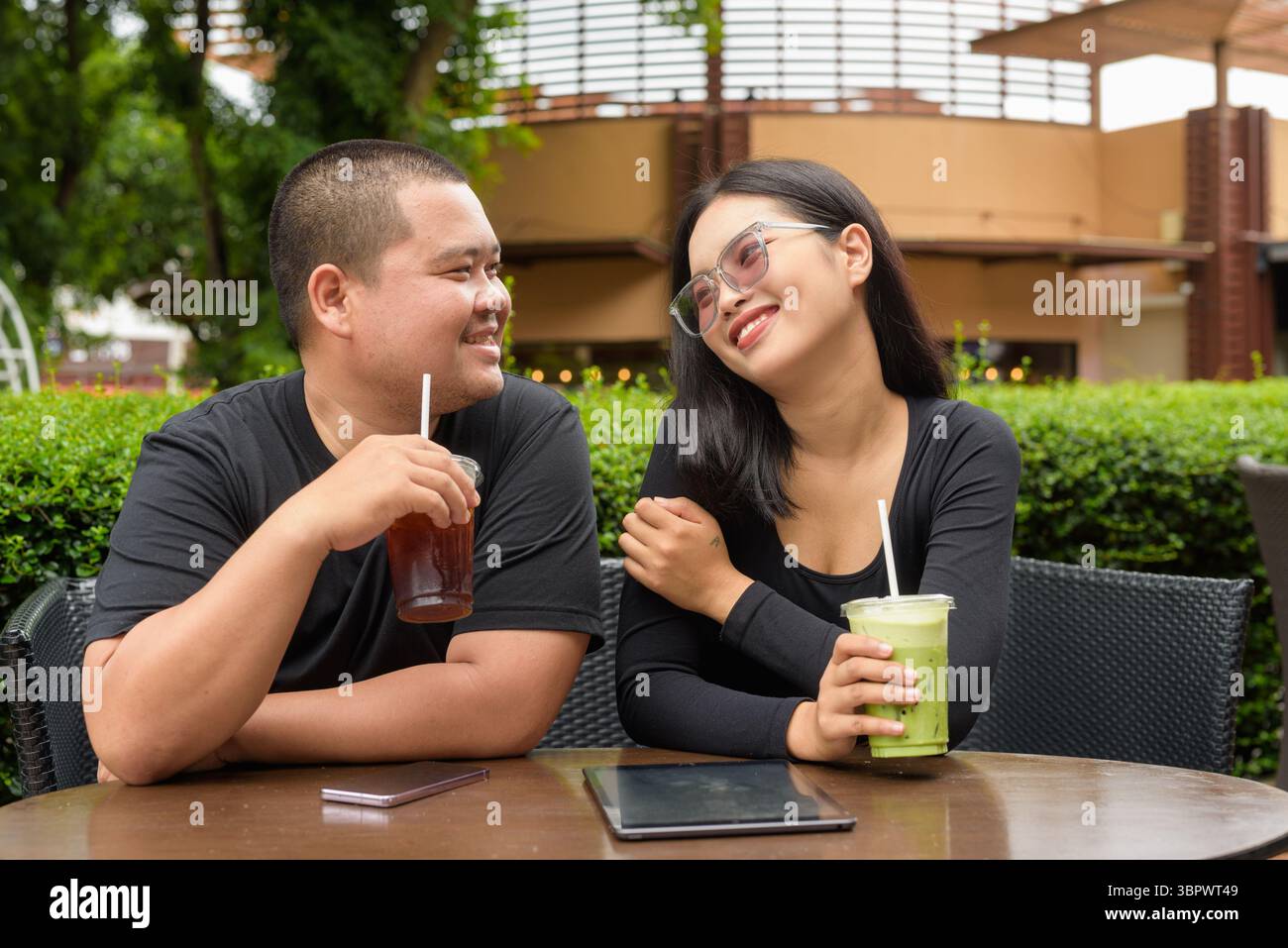 Felice coppia asiatica seduta insieme in un ristorante caffetteria all'aperto durante l'estate Foto Stock