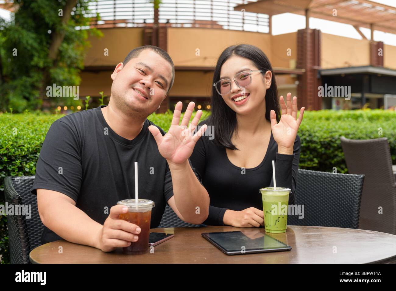Felice coppia asiatica seduta insieme in un ristorante caffetteria all'aperto durante l'estate Foto Stock