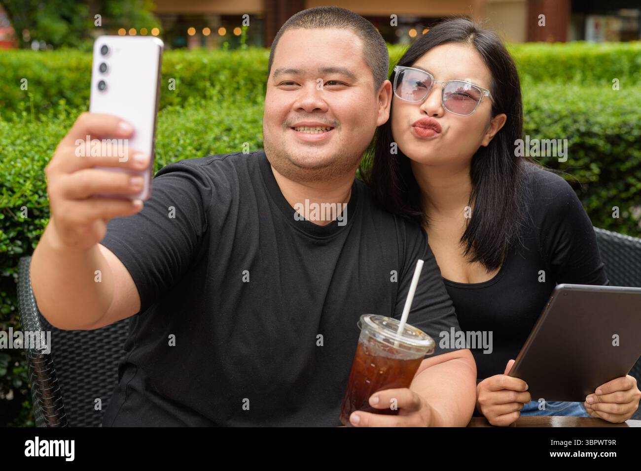 Felice coppia asiatica seduta insieme in un ristorante caffetteria all'aperto durante l'estate Foto Stock