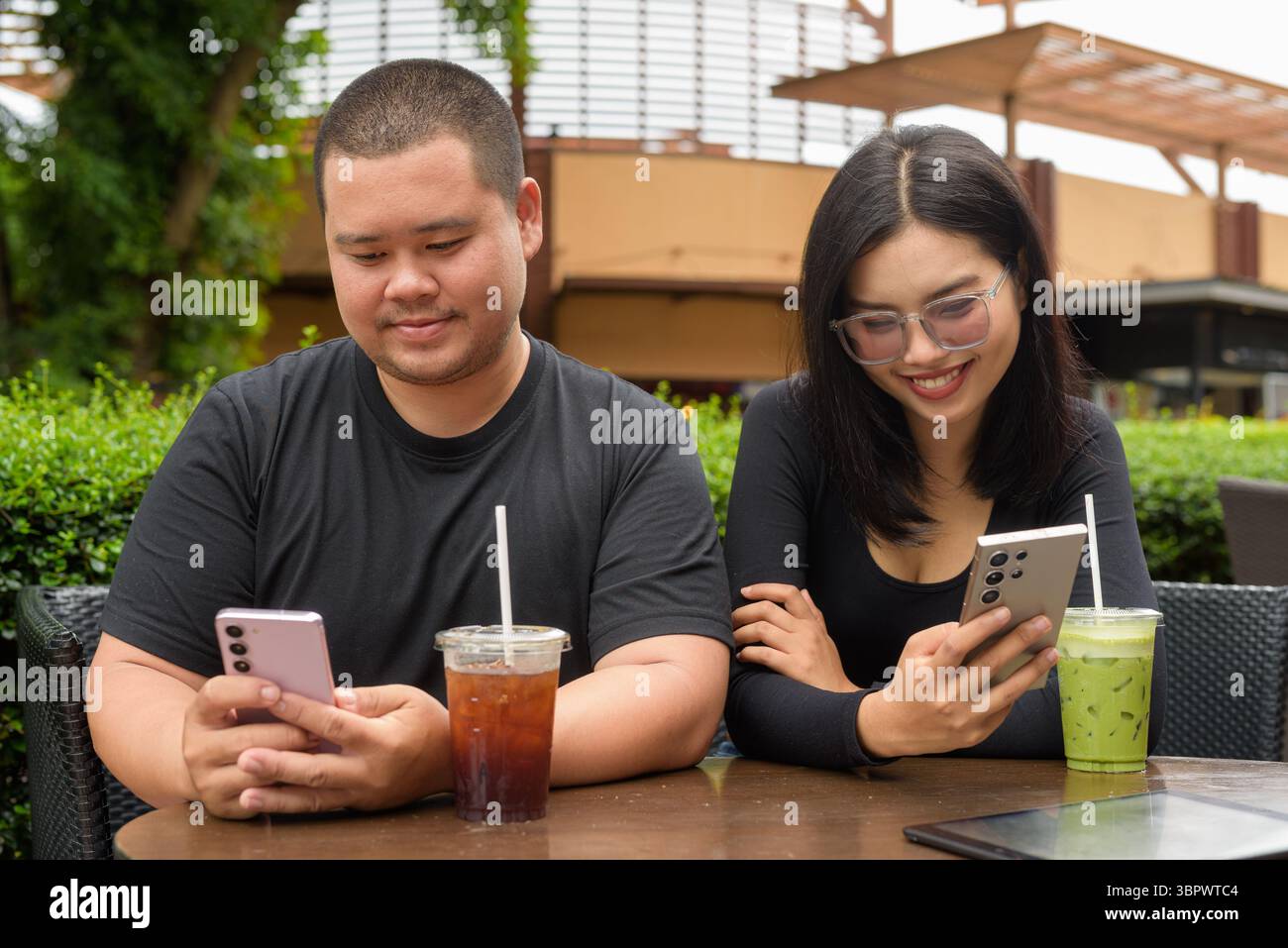 Felice coppia asiatica seduta insieme in un ristorante caffetteria all'aperto durante l'estate Foto Stock