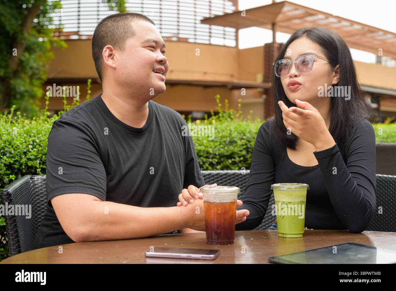 Felice coppia asiatica seduta insieme in un ristorante caffetteria all'aperto durante l'estate Foto Stock