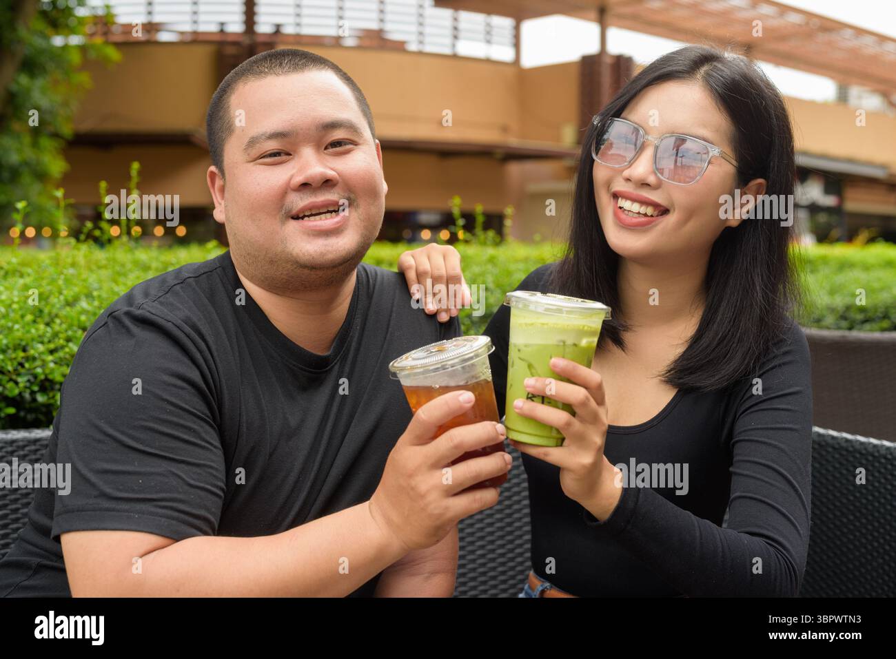 Felice coppia asiatica seduta insieme in un ristorante caffetteria all'aperto durante l'estate Foto Stock