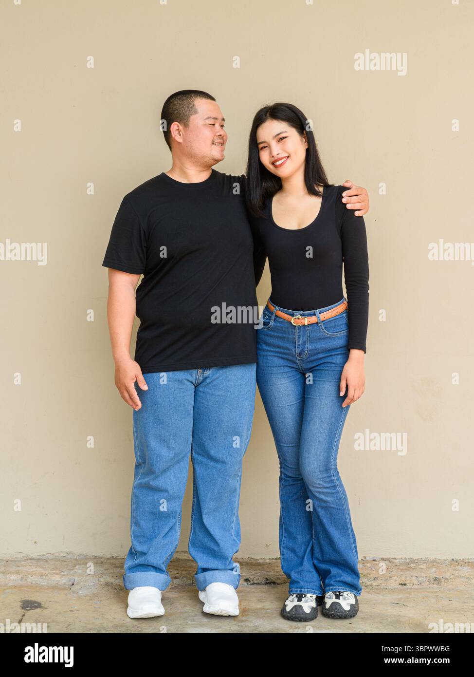 Ritratto a tutta lunghezza di giovani coppie asiatiche su un semplice sfondo murale Foto Stock