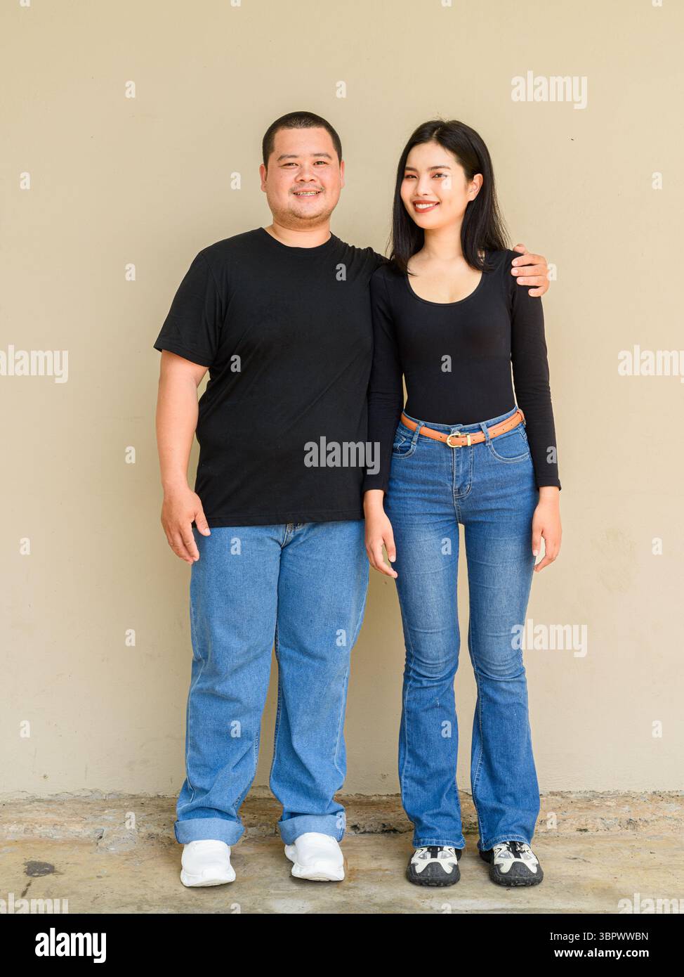 Ritratto a tutta lunghezza di giovani coppie asiatiche su un semplice sfondo murale Foto Stock