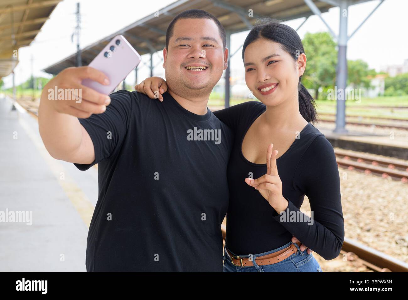 Giovane coppia asiatica in stazione ferroviaria insieme Foto Stock