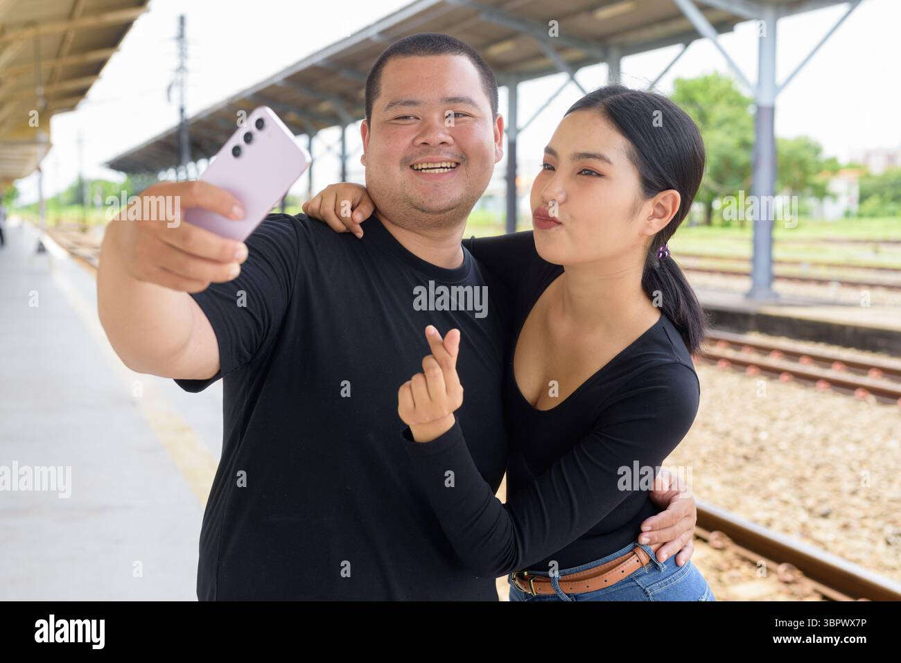 Giovane coppia asiatica in stazione ferroviaria insieme Foto Stock
