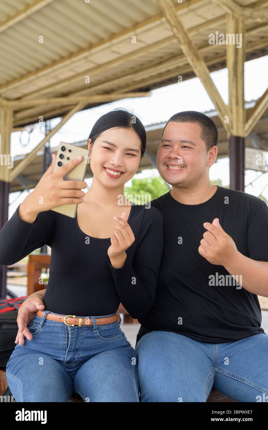 Giovane coppia asiatica in stazione ferroviaria insieme Foto Stock