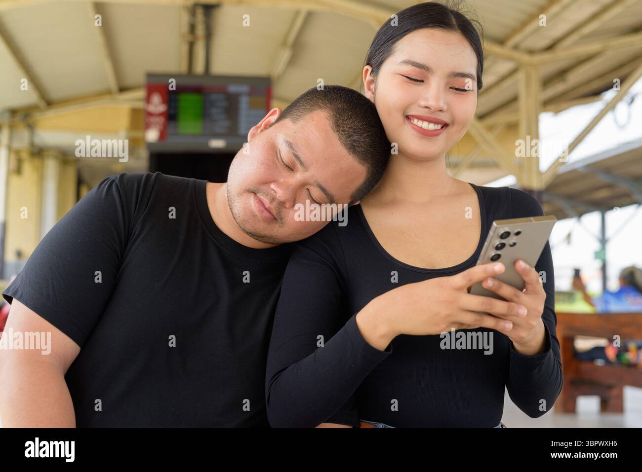 Giovane coppia asiatica in stazione ferroviaria insieme Foto Stock